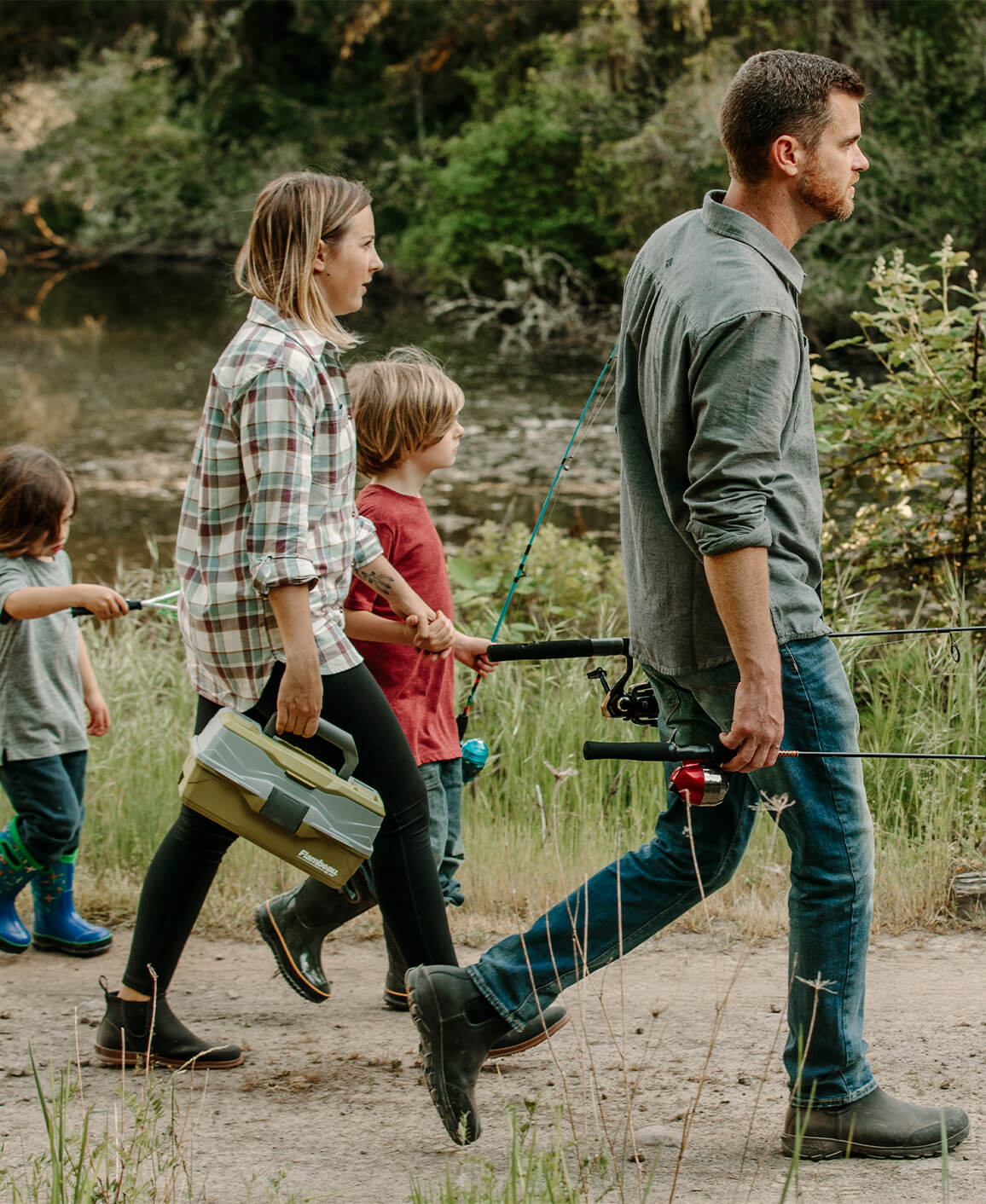 Image features a family walking by a body of water with fishing poles.